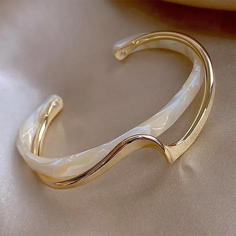 Elegant åbent armbånd lavet af hvid emalje og guld